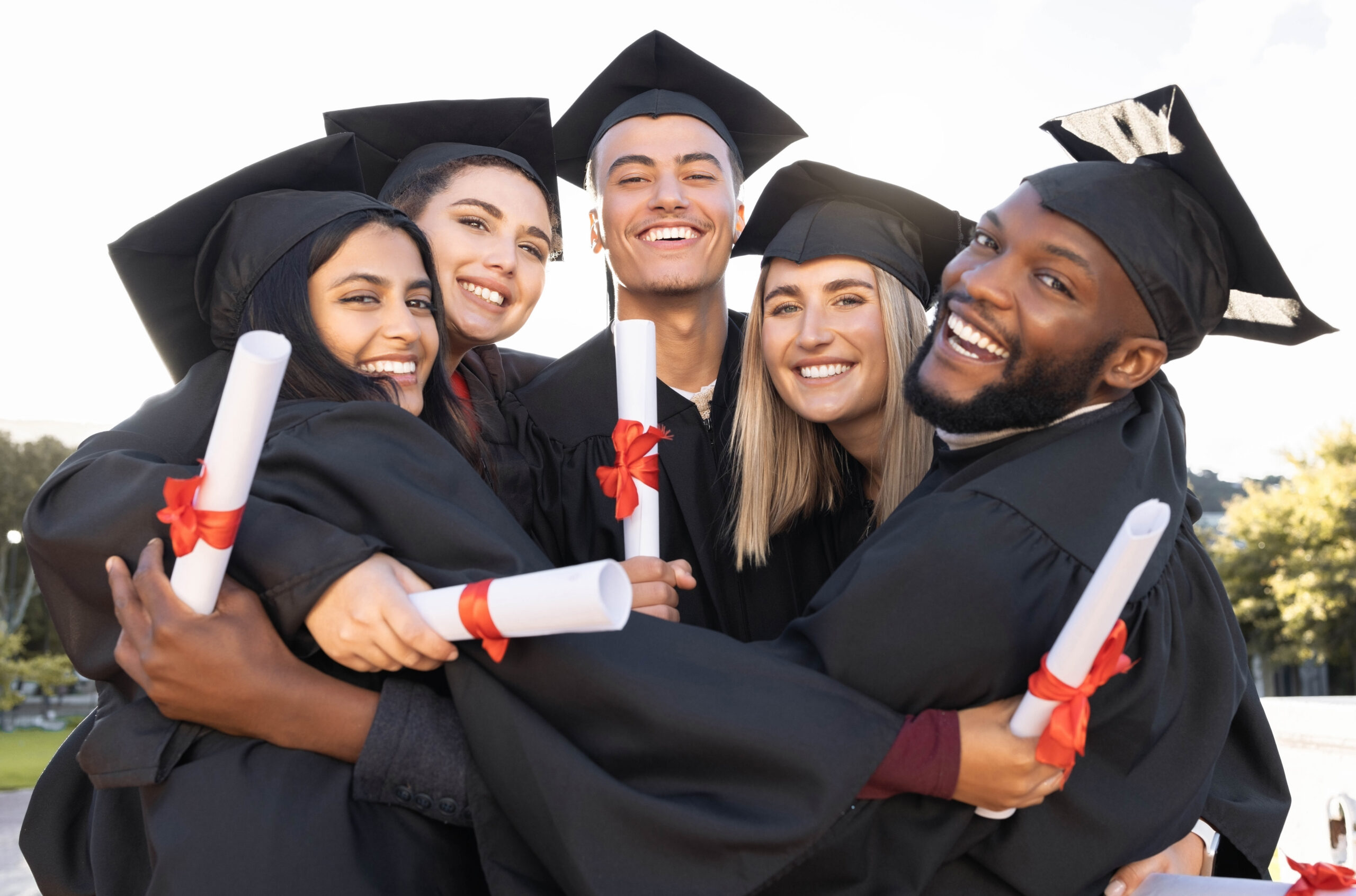 A group of happy new grads hugging each other.